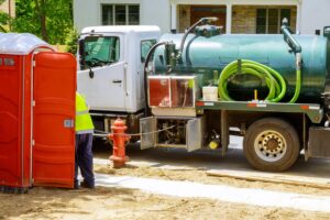 Sewage truck pumping feces out of rental toilet for disposal and cleaning at construction
